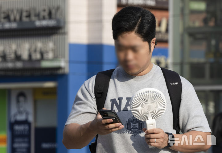 [서울=뉴시스] 김근수 기자 = 전국에 기록적인 폭염이 이어진 30일 오전 서울 서초구 고속버스터미널 인근에서 한 시민이 손풍기를 쐬며 출근길에 나서고 있다. 2025.07.30. ks@newsis.com