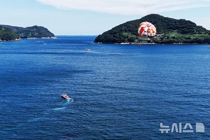 [남해=뉴시스] 차용현 기자 = 전국 대부분 지역에 폭염경보가 내려진 30일 오후 경남 남해군 원천마을 인근 해안에서 피서객들이 페러세일링을 타고 하늘을 날으며 더위를 식히고 있다. 2025.07.30. 2025.07.30.con@newsis.com