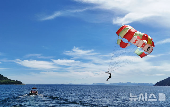 [남해=뉴시스] 차용현 기자 = 전국 대부분 지역에 폭염경보가 내려진 30일 오후 경남 남해군 원천마을 인근 해안에서 피서객들이 페러세일링을 타고 하늘을 날으며 더위를 식히고 있다. 2025.07.30. 2025.07.30.con@newsis.com