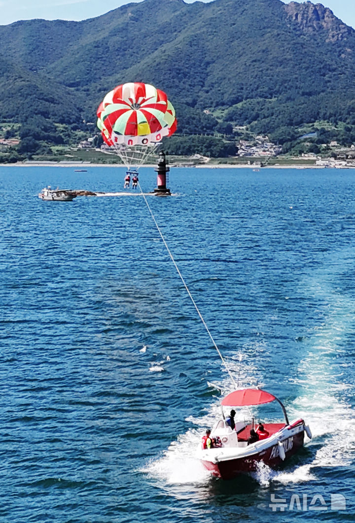 [남해=뉴시스] 차용현 기자 = 전국 대부분 지역에 폭염경보가 내려진 30일 오후 경남 남해군 원천마을 인근 해안에서 피서객들이 페러세일링을 타고 하늘을 날으며 더위를 식히고 있다. 2025.07.30. 2025.07.30.con@newsis.com