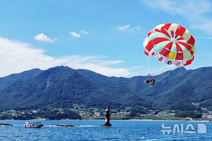 [남해=뉴시스] 차용현 기자 = 전국 대부분 지역에 폭염경보가 내려진 30일 오후 경남 남해군 원천마을 인근 해안에서 피서객들이 페러세일링을 타고 하늘을 날으며 더위를 식히고 있다. 2025.07.30. 2025.07.30.con@newsis.com