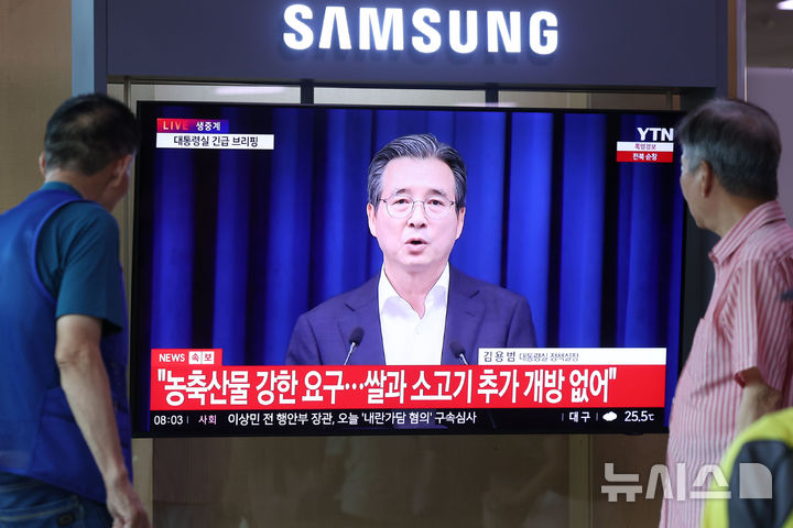 [서울=뉴시스] 권창회 기자 =미국과 관세 협상이 15%로 타결된 31일 오전 서울 용산구 서울역에서 시민들이 김용범 정책실장의 미국과 관세 협상 타결 관련 브리핑을 시청하고 있다. 2025.07.31. kch0523@newsis.com