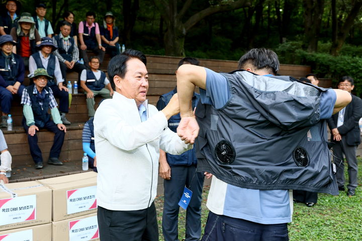 [서울=뉴시스] 이성헌 서대문구청장(왼쪽)이 한 푸른도시과 소속 현업 근로자가 보랭 조끼를 입는 것을 거들고 있다. 2025.08.01. (사진=서대문구 제공) *재판매 및 DB 금지