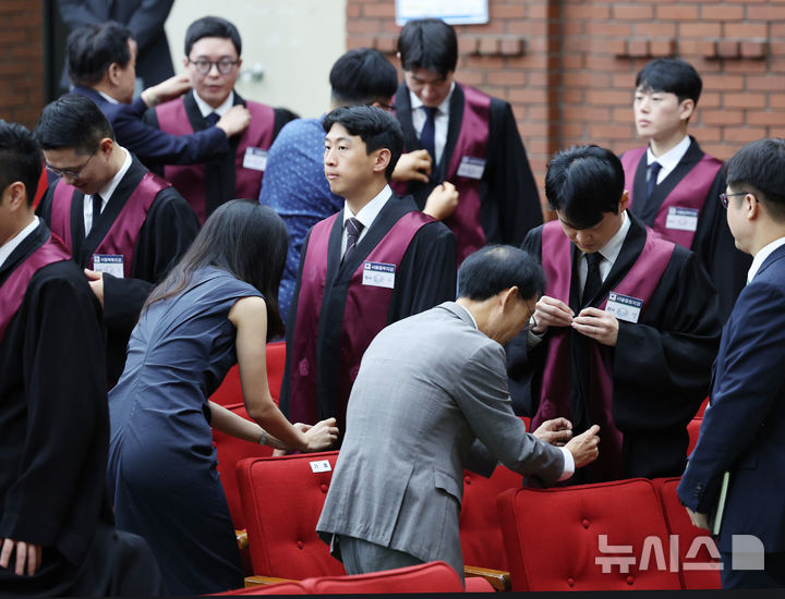 [과천=뉴시스] 김진아 기자 =  1일 경기 정부과천청사 법무부에서 열린 2025 하반기 신임검사 임관식에서 부모님들이 신임 검사들에게 법복을 입혀주고 있다. 2025.08.01. bluesoda@newsis.com
