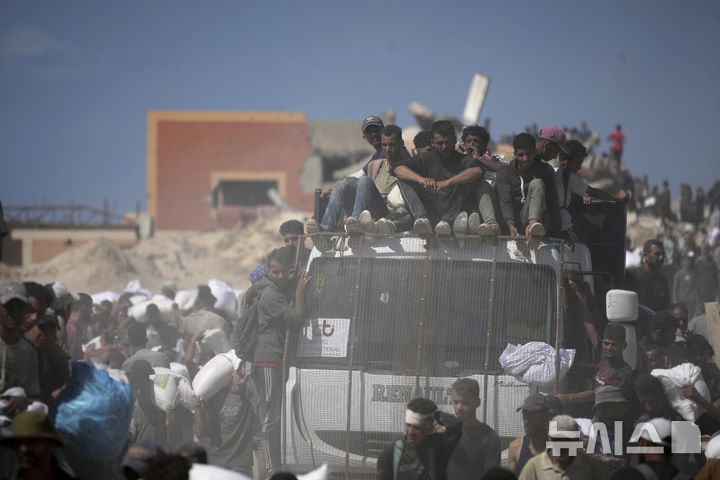 [베이트 라히야=AP/뉴시스] 1일(현지 시간) 가자지구 북부 베이트 라히야 외곽에서 팔레스타인 주민들이 가자시티로 향하던 인도적 물품 수송 트럭에서 내린 밀가루 자루를 나르고 있다. 2025.08.02.