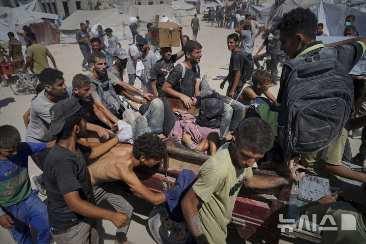 [베이트 라히야=AP/뉴시스] 1일(현지 시간) 가자지구 북부 베이트 라히야 외곽에서 팔레스타인 주민들이 가자시티로 향하던 인도적 물품 수송 트럭에 몰려들다 다친 부상자를 옮기고 있다. 2025.08.02.