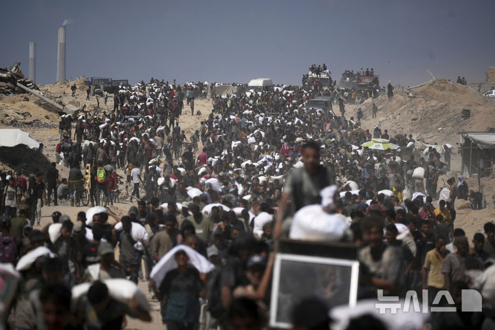 [베이트 라히야=AP/뉴시스] 1일(현지 시간) 가자지구 북부 베이트 라히야 외곽에서 팔레스타인 주민들이 가자시티로 향하던 인도적 물품 수송 트럭에서 내린 밀가루 자루를 나르고 있다. 2025.08.02.