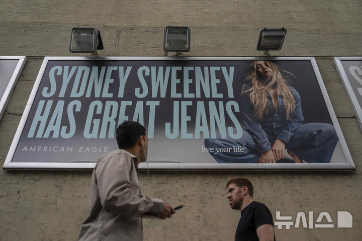 [뉴욕=AP/뉴시스] 사진은 지난 지난달 1일(현지 시간) 미국 뉴욕의 아메리칸 이글 매장 앞을 지나가는 시민들. 매장에는 시드니 스위니가 등장한 캠페인 포스터가 걸려 있다. 2025.08.04.