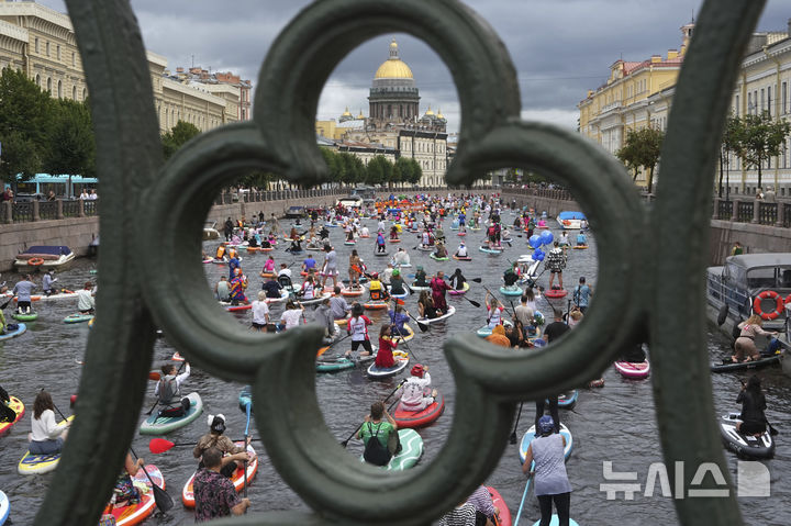 [상트페테르부르크=AP/뉴시스] 2일(현지 시간) 러시아 상트페테르부르크 모이카강에서 비가 내리는 가운데 열린 연례 ‘폰탄카’ 스탠드업 패들보드(SUP) 축제 참가자들이 패들보드를 젓고 있다. 이 축제에는 1만 명이 넘는 참가자가 함께했다. 2025.08.04.