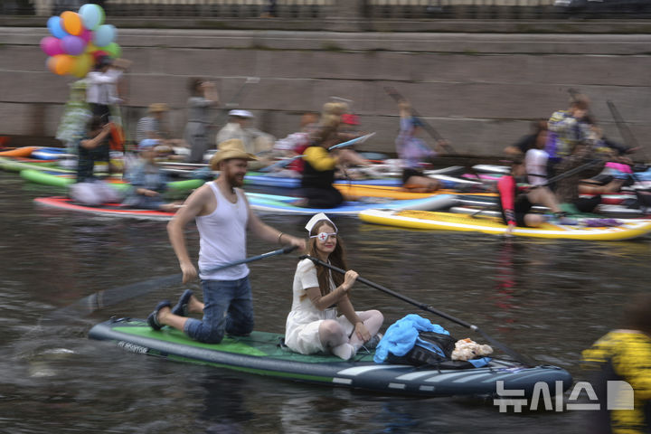 [상트페테르부르크=AP/뉴시스] 2일(현지 시간) 러시아 상트페테르부르크 모이카강에서 비가 내리는 가운데 열린 연례 ‘폰탄카’ 스탠드업 패들보드(SUP) 축제 참가자들이 패들보드를 젓고 있다. 이 축제에는 1만 명이 넘는 참가자가 함께했다. 2025.08.04.