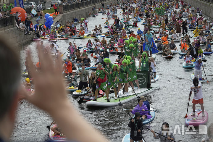 [상트페테르부르크=AP/뉴시스] 2일(현지 시간) 러시아 상트페테르부르크 모이카강에서 비가 내리는 가운데 열린 연례 ‘폰탄카’ 스탠드업 패들보드(SUP) 축제 참가자들이 패들보드를 젓고 있다. 이 축제에는 1만 명이 넘는 참가자가 함께했다. 2025.08.04.