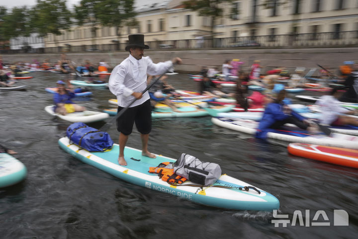 [상트페테르부르크=AP/뉴시스] 2일(현지 시간) 러시아 상트페테르부르크 모이카강에서 비가 내리는 가운데 열린 연례 ‘폰탄카’ 스탠드업 패들보드(SUP) 축제 참가자들이 패들보드를 젓고 있다. 이 축제에는 1만 명이 넘는 참가자가 함께했다. 2025.08.04.