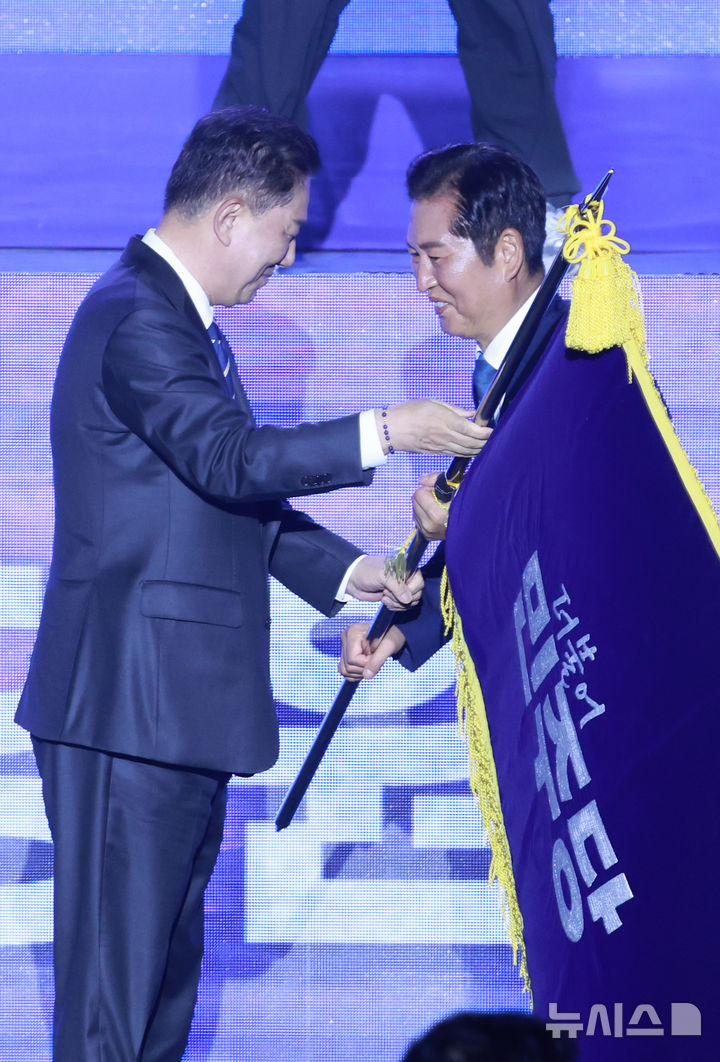 [고양=뉴시스] 고승민 기자 = 정청래 신임 더불어민주당 대표가 2일 경기 고양 킨텍스에서 열린 더불어민주당 제2차 임시전국당원대회에서 김병기 직무대행 겸 원내대표로부터 당기를 이양받고 있다. 2025.08.02. kkssmm99@newsis.com