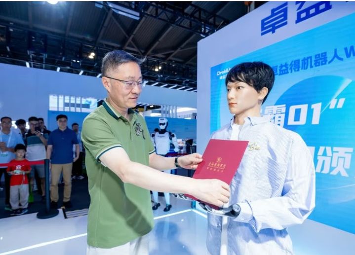  [서울=뉴시스] 상하이의 명문대 박사과정에 합격한 인간형 로봇 ‘쉐바 01’이 지난달 27일 상하이에서 열린 세계인공지능대회(WAIC)에서 ‘상하이 희곡 아카데미(STA)’ 관계자로부터 박사 과정 합격증을 받고 있다.(출처: SCMP) 2025.08.03. *재판매 및 DB 금지