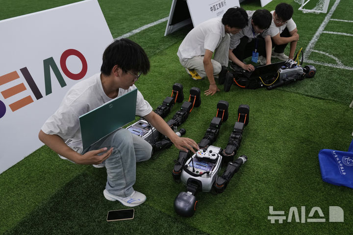 [베이징=AP/뉴시스] 4일(현지 시간) 중국 베이징에서 '2025 세계 휴머노이드 로봇 게임'을 앞두고 언론 공개 행사가 열린 가운데 부스터 휴머노이드 로봇 개발자들이 시스템 점검을 하고 있다. 오는 14일부터 17일까지 열리는 이 행사에는 축구를 비롯해 달리기, 격투, 댄스 등 실제 사람의 경기와 유사한 종목이 포함된 것으로 알려졌다. 2025.08.05.