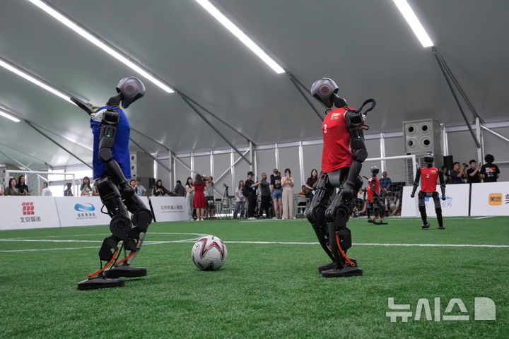 [베이징=AP/뉴시스] 4일(현지 시간) 중국 베이징에서 '2025 세계 휴머노이드 로봇 게임'을 앞두고 언론 공개 행사가 열린 가운데 부스터 휴머노이드 로봇들이 축구 시범 경기로 기술을 선보이고 있다. 오는 14일부터 17일까지 열리는 이 행사에는 축구를 비롯해 달리기, 격투, 댄스 등 실제 사람의 경기와 유사한 종목이 포함된 것으로 알려졌다. 2025.08.04.
