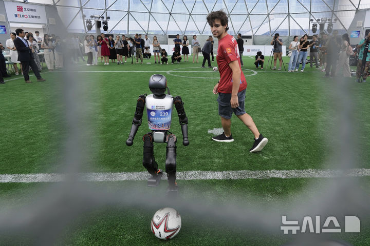[베이징=AP/뉴시스] 4일(현지 시간) 중국 베이징에서 열리는 '2025 세계 휴머노이드 로봇 게임'을 앞두고 언론 공개 행사가 열린 가운데 부스터 휴머노이드 로봇들이 축구 시범 경기로 기술을 선보이고 있다. 오는 14일부터 17일까지 열리는 이 행사에는 축구를 비롯해 달리기, 격투, 댄스 등 실제 사람의 경기와 유사한 종목이 포함된 것으로 알려졌다. 2025.08.04.