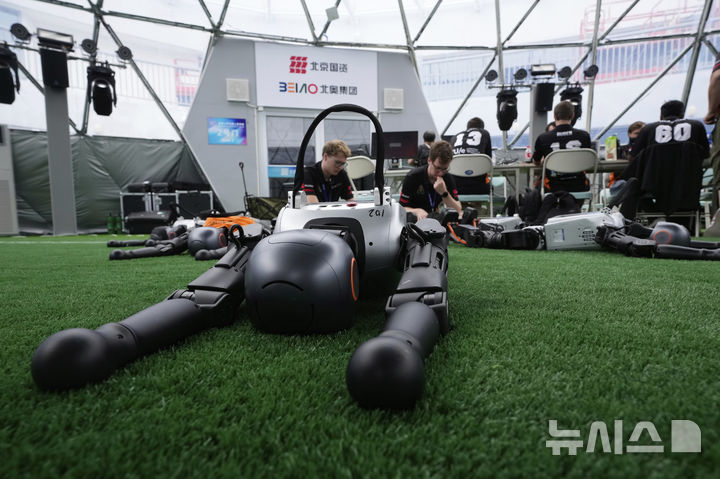 [베이징=AP/뉴시스] 4일(현지 시간) 중국 베이징에서 '2025 세계 휴머노이드 로봇 게임'을 앞두고 언론 공개 행사가 열린 가운데 부스터 휴머노이드 로봇 개발자들이 시스템 점검을 하고 있다. 오는 14일부터 17일까지 열리는 이 행사에는 축구를 비롯해 달리기, 격투, 댄스 등 실제 사람의 경기와 유사한 종목이 포함된 것으로 알려졌다. 2025.08.05.