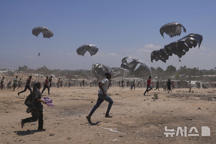 [자와이다=AP/뉴시스] 4일(현지 시간) 가자지구 중부 자와이다에서 팔레스타인 주민들이 낙하산으로 투하되는 인도적 지원 물품을 받기 위해 몰려들고 있다. 2025.08.05.
