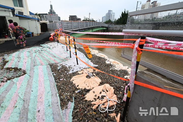 [광주=뉴시스] 이영주 기자 = 4일 오전 광주 북구 신안동 서암대로 100번길 주변 무너진 투명홍수방어벽 주변으로 주민들이 모여 있다. 주민들은 지난달 17일 426㎜폭우가 쏟아졌을 당시 투명홍수방어벽이 물그릇 역할을 하면서 마을이 침수됐다고 주장, 당국을 상대로 소송에 나설 방침이다. 2025.08.04. leey2578@newsis.com