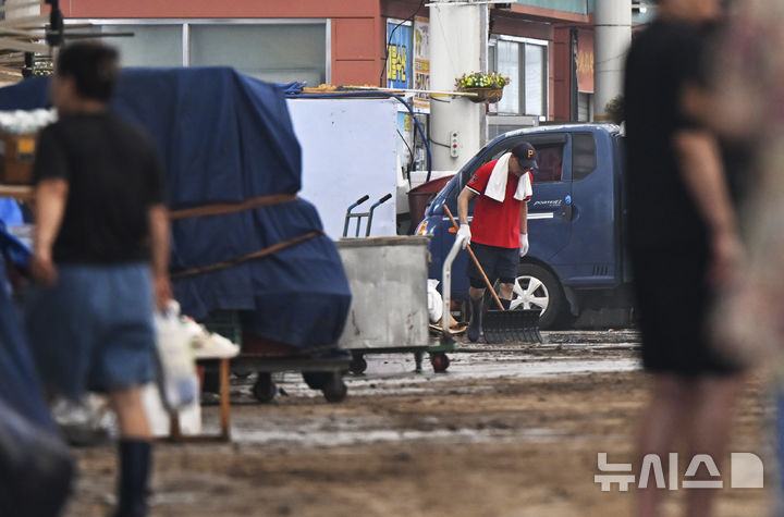 [함평=뉴시스] 박기웅 기자 = 4일 오전 전남 함평군 함평읍 함평천지전통시장 상인들이 흙탕물로 뒤덮인 거리를 청소하고 있다. 함평에는 전날 많은 비가 내리면서 주택 50가구와 상가 46곳이 침수된 것으로 잠정 집계됐다. 2025.08.04. pboxer@newsis.com