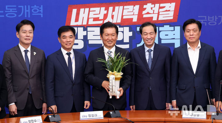 [서울=뉴시스] 김금보 기자 = 우상호(오른쪽 두번째) 정무수석이 4일 오후 서울 여의도 국회에서 정청래(가운데) 더불어민주당 당대표에게 대통령이 보낸 당대표 취임 축하난을 전달한 뒤 기념촬영을 하고 있다. 2025.08.04. kgb@newsis.com