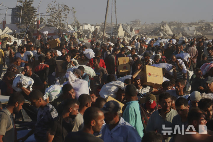 [라파=AP/뉴시스] 4일(현지 시간) 가자지구 남부 라파 인근에서 팔레스타인 주민들이 모라그 회랑을 따라 이동하는 인도주의 구호 물품 수송 트럭에서 가져온 구호 물품을 옮기고 있다. 2025.08.05.