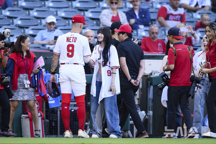 [애너하임=AP/뉴시스] 걸그룹 '아이들' 멤버 민니(가운데)가 4일(현지 시간) 미 캘리포니아주 애너하임의 에인절 스타디움에서 열린 2025 메이저리그 탬파베이 레이스와 LA 에인절스의 경기에 앞서 LA 에인절스 잭 네토와 인사하고 있다. 2025.08.05.