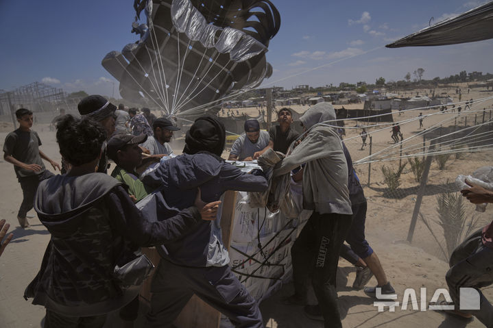 [데이르알발라=AP/뉴시스] 5일(현지 시간) 가자지구 중부 데이르알발라에서 팔레스타인 주민들이 낙하산으로 투하된 인도적 지원 물품에 몰려들고 있다. 2025.08.06.