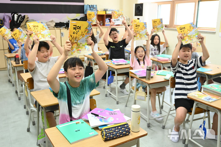 [수원=뉴시스] 김종택 기자 = 5일 여름방학을 마치고 개학한 경기 수원시 영통구 잠원초등학교 4학년2반 학생들이 새학기 교과서를 들어 보이며 즐거워하고 있다. 2025.08.05. jtk@newsis.com