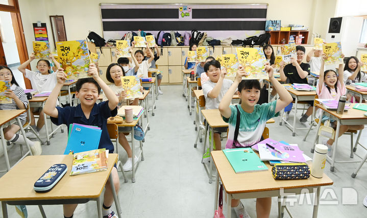 [수원=뉴시스] 김종택 기자 = 5일 여름방학을 마치고 개학한 경기 수원시 영통구 잠원초등학교 4학년2반 학생들이 새학기 교과서를 들어 보이며 즐거워하고 있다. 2025.08.05. jtk@newsis.com