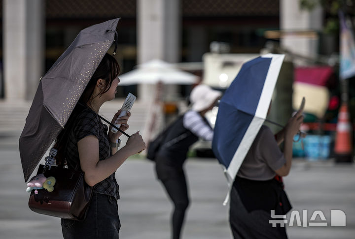 [서울=뉴시스] 정병혁 기자 = 더운 날씨가 이어지고 있는 5일 서울 종로구 광화문광장에서 여행객들이 양산을 쓴 채 사진을 찍고 있다. 2025.08.05. jhope@newsis.com