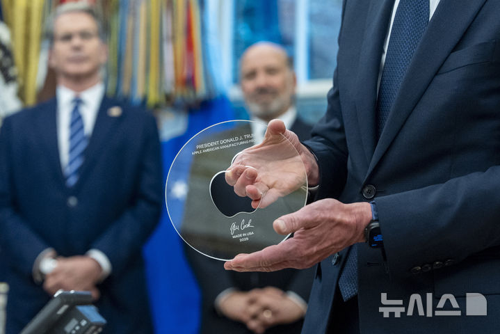 [워싱턴=AP/뉴시스] 6일(현지 시간) 미 워싱턴 DC 백악관 오벌 오피스에서 팀 쿡 애플 CEO가 도널드 트럼프 대통령에게 전달할 선물을 들어보이고 있다. 애플은 이날 국내 사업에 4년간 총 6000억 달러(831조3000억원)를 투자한다고 밝혔다. 2025.08.07.