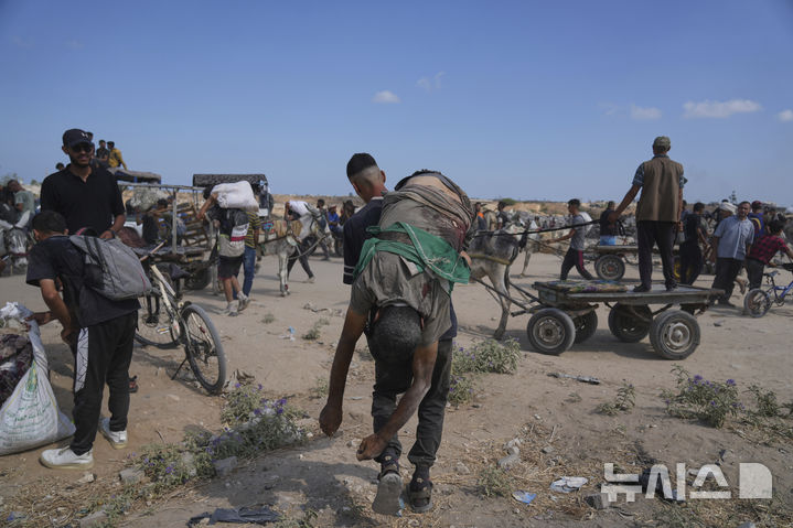 [AP/뉴시스] 지난 4일 사진으로 가자 지구 중부 네차림 인근에 설치된 미국 민간조직 '가자 인도주의재단(GHF)' 배급처에서 식량을 얻으려다 죽은 팔레스타인 주민을 누군가 등에 메고 가고 있다. 5월 27일 GHF 배급 실시 이래 이렇게 목숨을 잃은 가자인이 900명을 넘었다.  