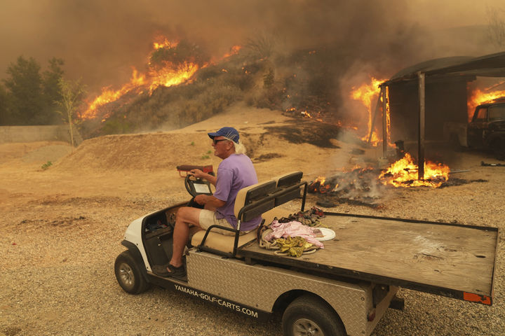 [할시 캐니언=AP/뉴시스] 7일(현지 시간) 미 캘리포니아주 할시 캐니언에서 한 주민이 골프 카트를 타고 '캐니언 파이어' 산불이 번지는 집에서 대피하고 있다. 2025.08.08.