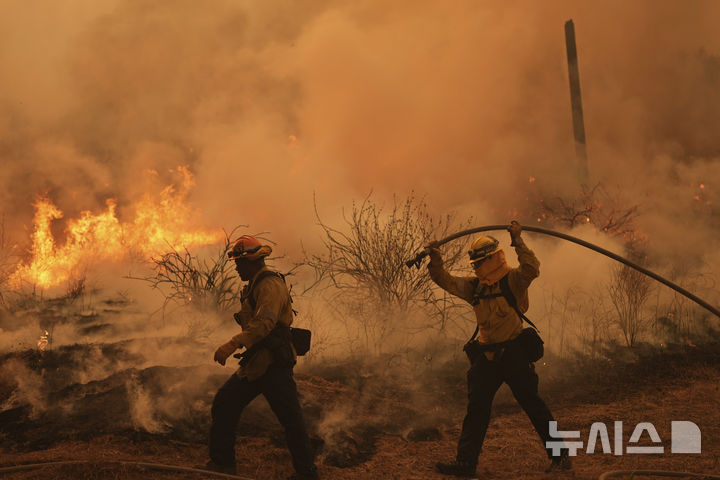[로스앤젤레스=AP/뉴시스] 미국 캘리포니아주 로스앤젤레스(LA) 북쪽에서 7일 발생한 산불 현장에서 소방 대원들이 붉은 화염속에 물을 뿌리고 있다. 2025.08.09. 