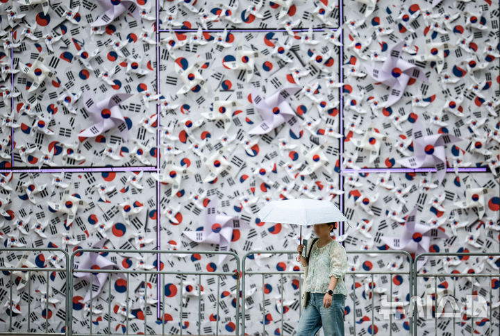 [서울=뉴시스] 정병혁 기자 = 8일 서울 중구 서울광장에 조성된 태극기 언덕 앞에서 한 시민이 이동하고 있다. 2025.08.08. jhope@newsis.com
