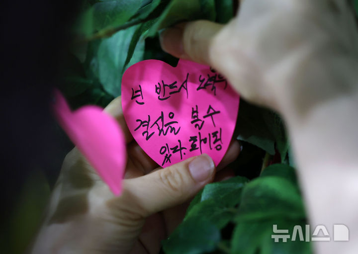 [서울=뉴시스] 홍효식 기자 = 9일 서울 중구 서울시청에서 열린 2026 서울런 수시 입학 정보 박람회 및 설명회를 찾은 한 학부모가 진학 다짐 메시지를 달고 있다.이번 박람회는 수도권과 비수도권 4년제 대학 27곳이 참여했으며, 사전 신청한 수험생들은 최대 2개 대학을 선택해 각 대학 입학사정관과 20분간 1:1 맞춤형 상담을 진행했다. 2025.08.09. yesphoto@newsis.com