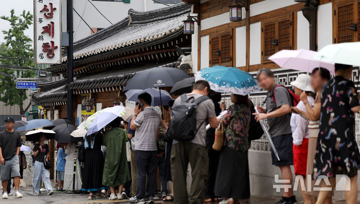 [서울=뉴시스] 홍효식 기자 = 말복인 9일 서울 종로구 한 삼계탕 전문점을 찾은 사람들이 우산을 쓰고 입장을 기다리고 있다. 2025.08.09. yesphoto@newsis.com