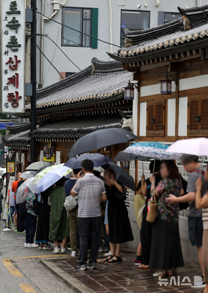 [서울=뉴시스] 홍효식 기자 = 말복인 9일 서울 종로구 한 삼계탕 전문점을 찾은 사람들이 우산을 쓰고 입장을 기다리고 있다. 2025.08.09. yesphoto@newsis.com