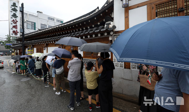 [서울=뉴시스] 홍효식 기자 = 말복인 9일 서울 종로구 한 삼계탕 전문점을 찾은 사람들이 우산을 쓰고 입장을 기다리고 있다. 2025.08.09. yesphoto@newsis.com