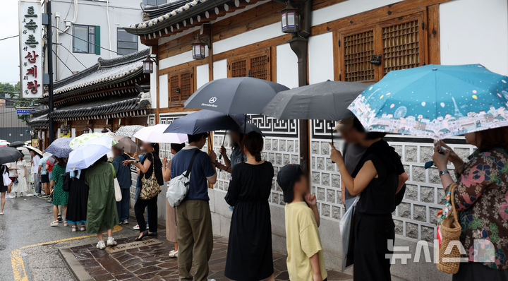 [서울=뉴시스] 홍효식 기자 = 말복인 9일 서울 종로구 한 삼계탕 전문점을 찾은 사람들이 우산을 쓰고 입장을 기다리고 있다. 2025.08.09. yesphoto@newsis.com