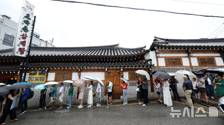 [서울=뉴시스] 홍효식 기자 = 말복인 9일 서울 종로구 한 삼계탕 전문점을 찾은 사람들이 우산을 쓰고 입장을 기다리고 있다. 2025.08.09. yesphoto@newsis.com