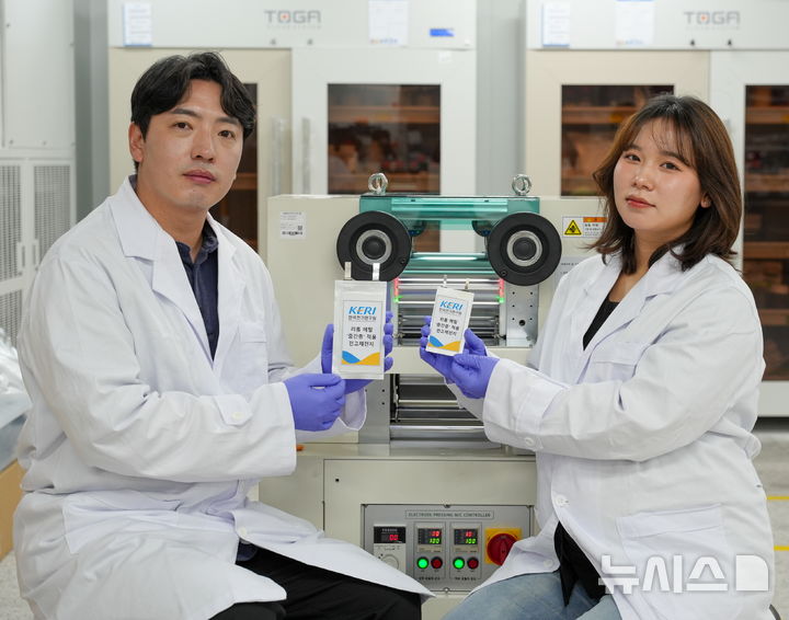 [창원=뉴시스]한국전기연구원(KERI) 전지소재·공정연구센터 남기훈 박사(왼쪽)와 김가람 연구원(UST 석사과정 졸업)이 중간층을 만드는 롤프레스 장비 앞에서 '리튬 메탈 중간층 적용 전고체전지 음극 소재' 성과물을 선보이고 있다.(사진=KERI 제공) 2025.08.11. photo@newsis.com