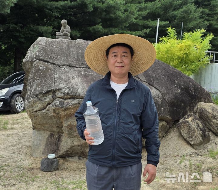 [김천=뉴시스] 박홍식 기자 = 왕두꺼비 산장 식당 마당에 있는 두꺼비 바위 앞에서 천연 아연이 함유된 금율약수를 들고 있는 신승우 대표. 2025.08.11 phs6431@newsis.com