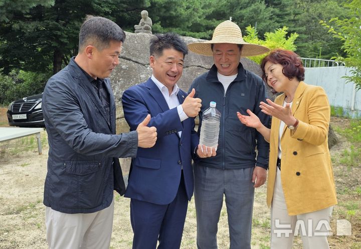[김천=뉴시스] 박홍식 기자 = 왕두꺼비 산장 식당 마당에 있는 두꺼비 바위 앞에서 금율약수를 들고 기념사진을 찍는 배형태(왼쪽부터) 김천시의원, 나영민 김천시의장, 신승우 대표. 김응숙 김천시의원. 2025.08.11 phs6431@newsis.com