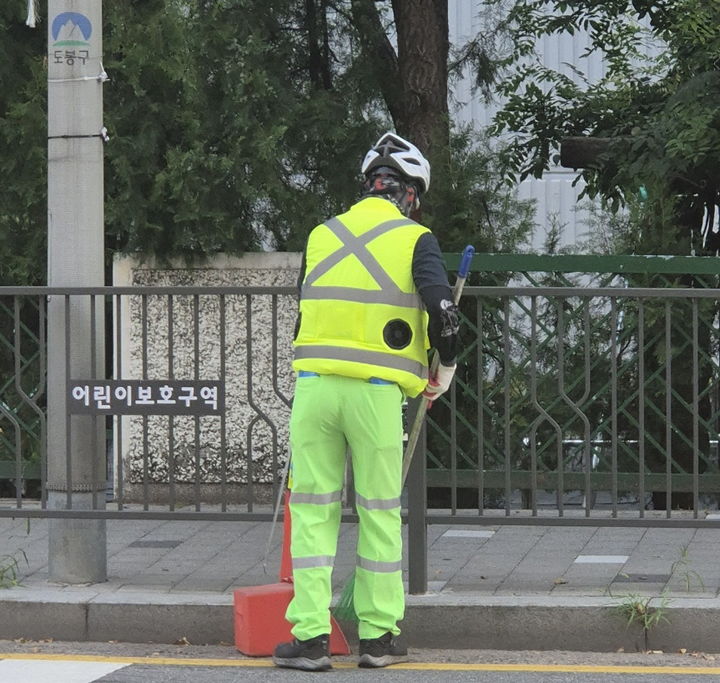 [서울=뉴시스] 도봉구 야외 청소 현업근로자가 선풍기 조끼를 입고 도봉구 지역 내 한 도로를 청소하고 있다. 2025.08.11. (사진=도봉구 제공) *재판매 및 DB 금지