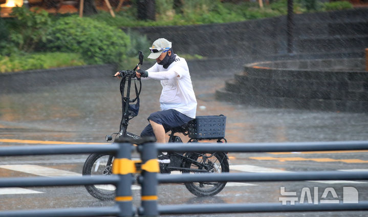 [제주=뉴시스] 우장호 기자 = 정체전선 영향으로 호우특보가 내려진 11일 오전 제주시 노형오거리 인근 거리에서 전기자전거를 탄 시민이 비를 피해 이동하고 있다. 2025.08.11. woo1223@newsis.com