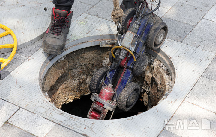 [서울=뉴시스] 홍효식 기자 = 서울시 물재생계획과 관계자들이 지반침하 대응 노후 하수관로 종합정밀조사를 위해 소형 카메라가 장착된 하수관로 자주차를 맨홀에 투입하고 있다. 기사내용과 관계 없음. 2025.08.13. yesphoto@newsis.com