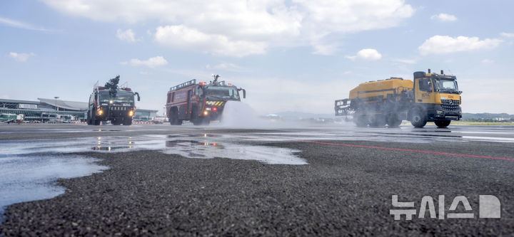 [서울=뉴시스] 김선웅 기자 = 12일 서울 강서구 김포국제공항 국내선 이동지역에서 한국공항공사 관계자들이 소방차를 이용해 폭염 대비 계류장 살수작업을 하고 있다. 살수작업은 활주로 등 이동지역 포장면의 표면온도가 60도 이상일 경우 물을 살포해 온도를 약 10도 가량 낮추어 포장 손상 위험을 줄이고 항공기 운항 안전성을 높이는 효과가 있다. 한국공항공사는 폭염경보가 발령될 경우 항공기 이동지역 포장면의 온도를 하루 세 차례 측정해 살수작업 여부를 결정한다. 2025.08.12. mangusta@newsis.com